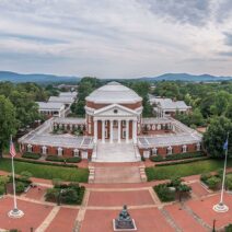 Arial-view-of-a-university-campus-featuring-a-neoclassical-rotunda-surrounded-by-lush-greenery-and-mountains-in-the-background