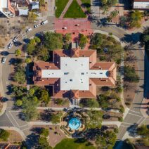 Top-down-view-of-a-university-campus-building-with-a-central-fountain-surrounded-by-trees-and-palm-lined-walkways